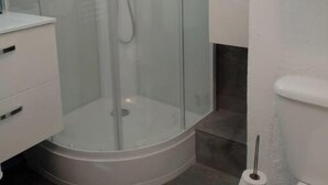 A bathroom with a glass-enclosed shower, a white toilet, and a white sink with a mirror. - COSY & MODERN STUDIO NEAR PORT (Agde)