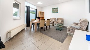 A room with a dining table, chairs, a sofa, a radiator, and a window. - Holiday Apartment “SaarGlück” with Mountain Views and Wi-Fi (Beckingen)