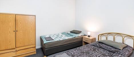 Un dormitorio con cama, armario, mesita de noche y lámpara.