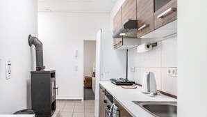A compact kitchen with a built-in stove, a sink, and wooden cabinets. - Holiday Apartment “SaarGlück” with Mountain Views and Wi-Fi (Beckingen)