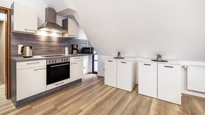 Een moderne keuken met witte kasten, een ingebouwde oven en een magnetron.