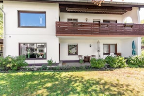 Ein zweigeschossiges Haus mit Balkon, kleinem Garten und der Hausnummer 52 an der Wand.