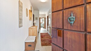 A hallway with wooden cabinets, a radiator, a wooden bench, and a red rug. - Wanderbar Apartment on the Rhine with Private Terrace, Garden, and Wi-Fi (Kamp-Bornhofen)