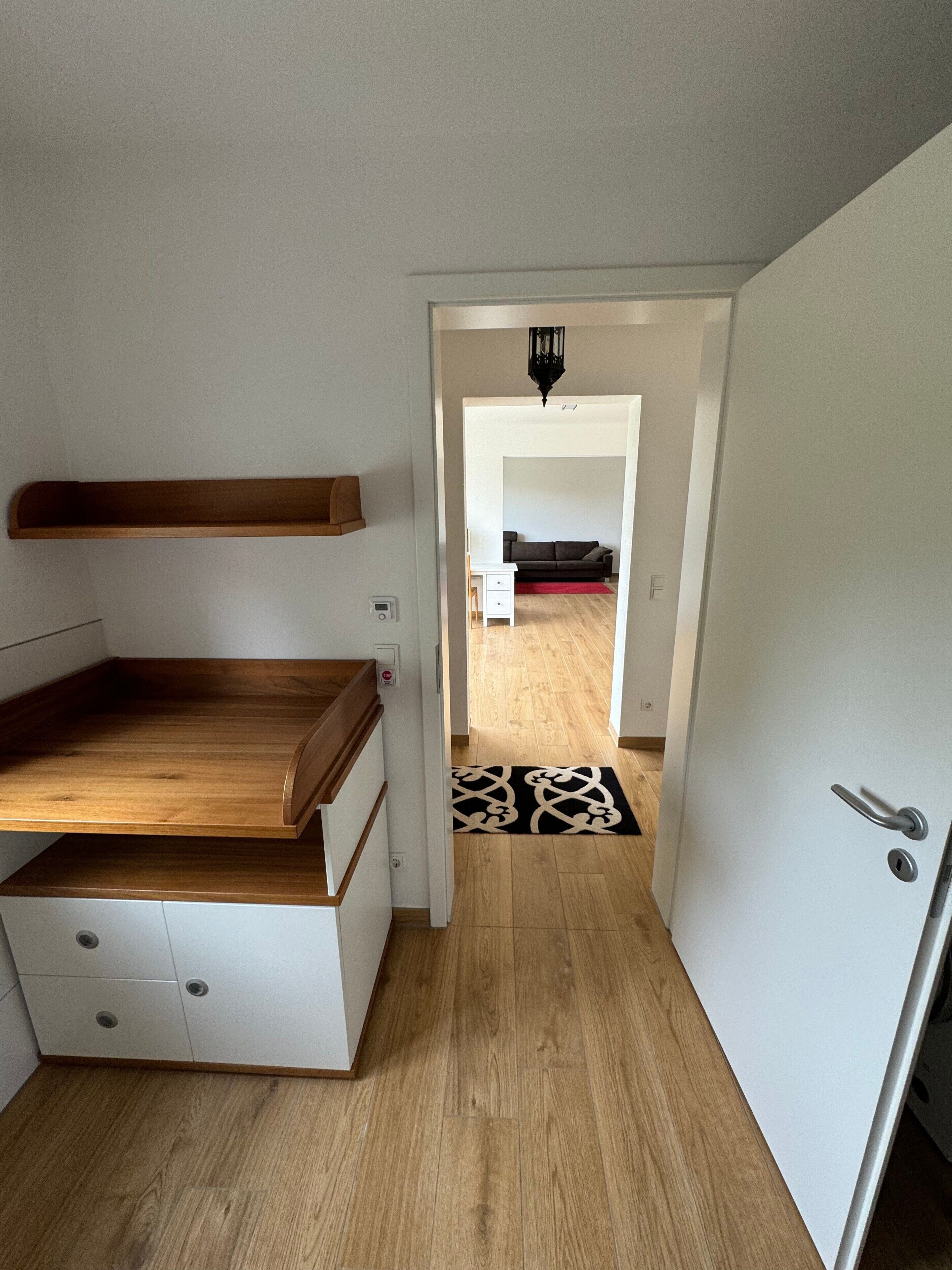 A compact room with a wooden desk, a white cabinet, and a door leading to another room.