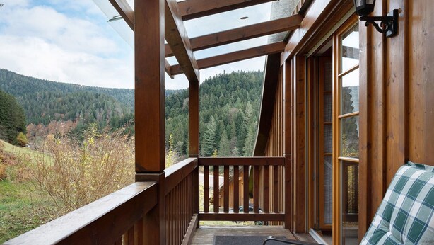 Une terrasse en bois offrant une vue sur une chaîne de montagnes boisées.