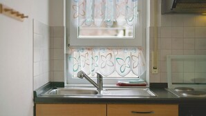 Eine Küche mit Spüle, einem Fenster mit dekorativen Vorhängen und einem Herd.