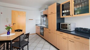 Eine kleine Küche mit Holzausstattung, einer Mikrowelle und einem Essbereich mit Tisch und Stühlen.
