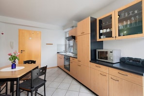 A compact kitchen with wooden cabinets, a microwave, and a dining area with a table and chairs.
