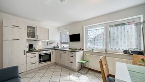 A modern kitchen with light wood cabinets, a built-in oven, and a dining area with a table and chairs. - Apartment '2' with Private Terrace and Wi-Fi in Endingen (Endingen)