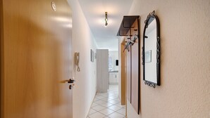 A hallway with a wooden door, a mirror, and a tiled floor leading to a kitchen area. - Apartment '2' with Private Terrace and Wi-Fi in Endingen (Endingen)
