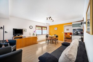 A modern living room with a sofa, TV, wooden cabinet, dining table, and chairs. - Apartment '1' with Terrace and Wi-Fi (Endingen am Kaiserstuhl)