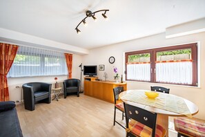 A room with a dining table, chairs, a TV, a small side table, and a sofa. - Apartment '1' with Terrace and Wi-Fi (Endingen am Kaiserstuhl)