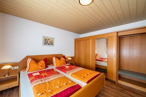 A hotel room with a wooden bed, a nightstand, a wardrobe, and a mirror. - Apartment '1' with Terrace and Wi-Fi (Endingen am Kaiserstuhl)