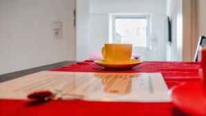 Una tazza gialla su un tavolo rosso, con un documento e una penna.