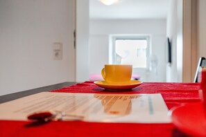 Een gele beker op een rode tafel, met een document en een pen.