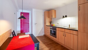 Una cucina compatta con mobili in legno, un piano di lavoro nero e un tavolo rosso.