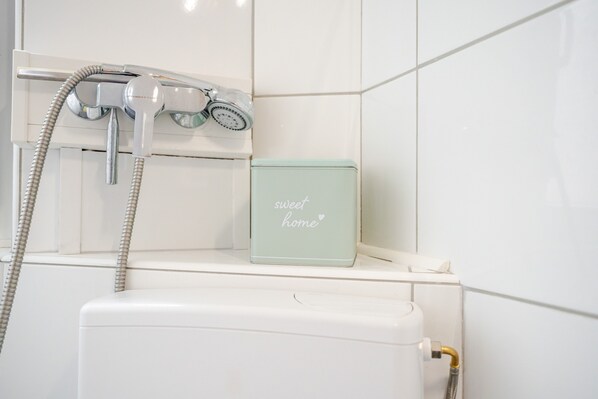 A bathroom with a shower, a toilet, and a shelf with a box labeled 'sweet home'.