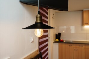 A kitchen with wooden cabinets, a black hanging light fixture, and a striped wall.