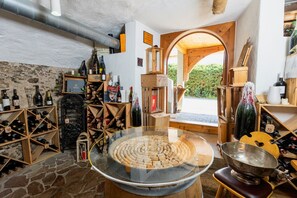 Une cave à vin avec des étagères en bois, un grand présentoir à vin en verre et un espace dédié à la dégustation de vins.