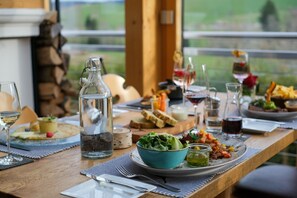 A dining table set with plates, glasses, and a variety of dishes, including a salad and a dessert, in a room with a view. - Room 'Doppelzimmer 1' with Mountain View, Balcony and Wi-Fi (Bernau im Schwarzwald)