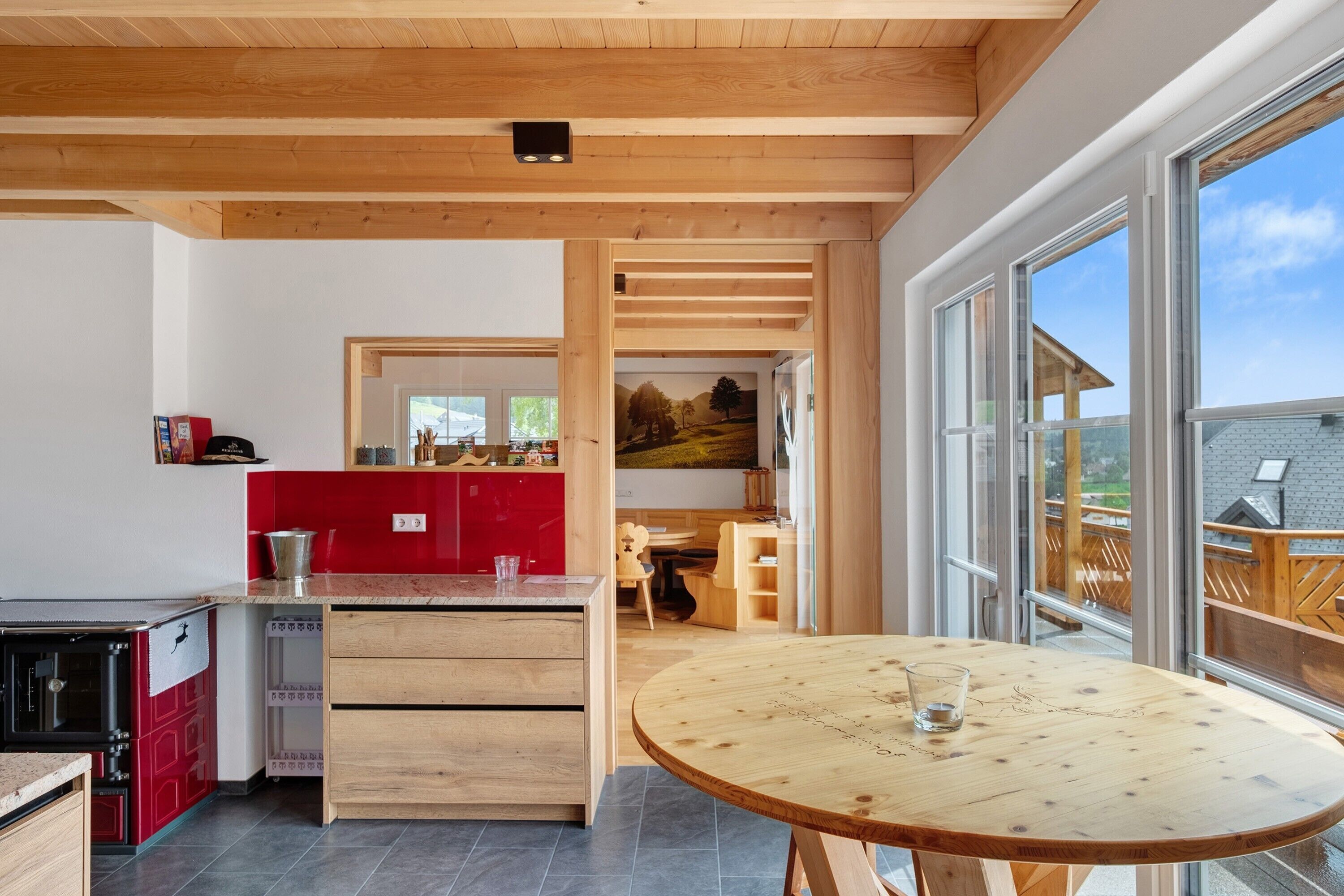 Eine moderne Küche mit Holzschränken, einem roten Kühlschrank und einem Essbereich mit einem runden Holztisch.
