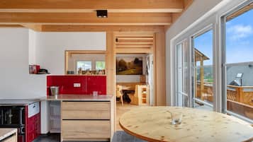 Eine moderne Küche mit Holzschränken, einem roten Kühlschrank und einem Essbereich mit einem runden Holztisch.