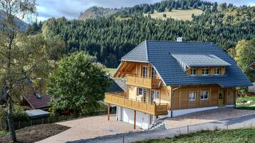 Ein zweistöckiges Holzhaus mit Balkon, Garage und Auffahrt zu einer Straße.