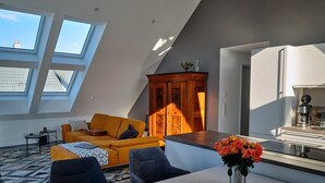 A modern loft apartment with a dining area, kitchen, and a large window.
