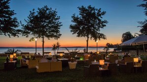 Outdoor seating with tables and chairs, a view of the water, and a sunset.