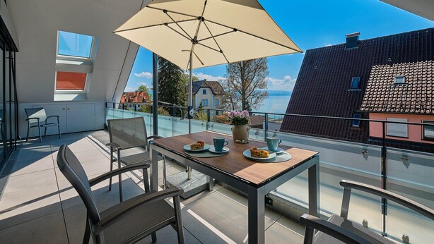A balcony with a table, chairs, and a large umbrella.