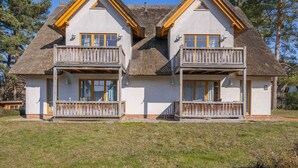 Un bâtiment à deux étages, doté d’un toit de chaume, de balcons en bois et d’une façade blanche.