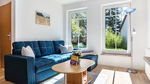 A modern living room with a blue sofa, a wooden coffee table, and a floor lamp.