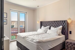Une chambre avec un grand lit, un balcon et une vue sur les immeubles.