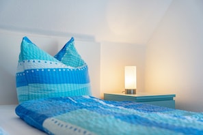 A bedroom with a bed, pillows, a bedside table, and a nightstand.
