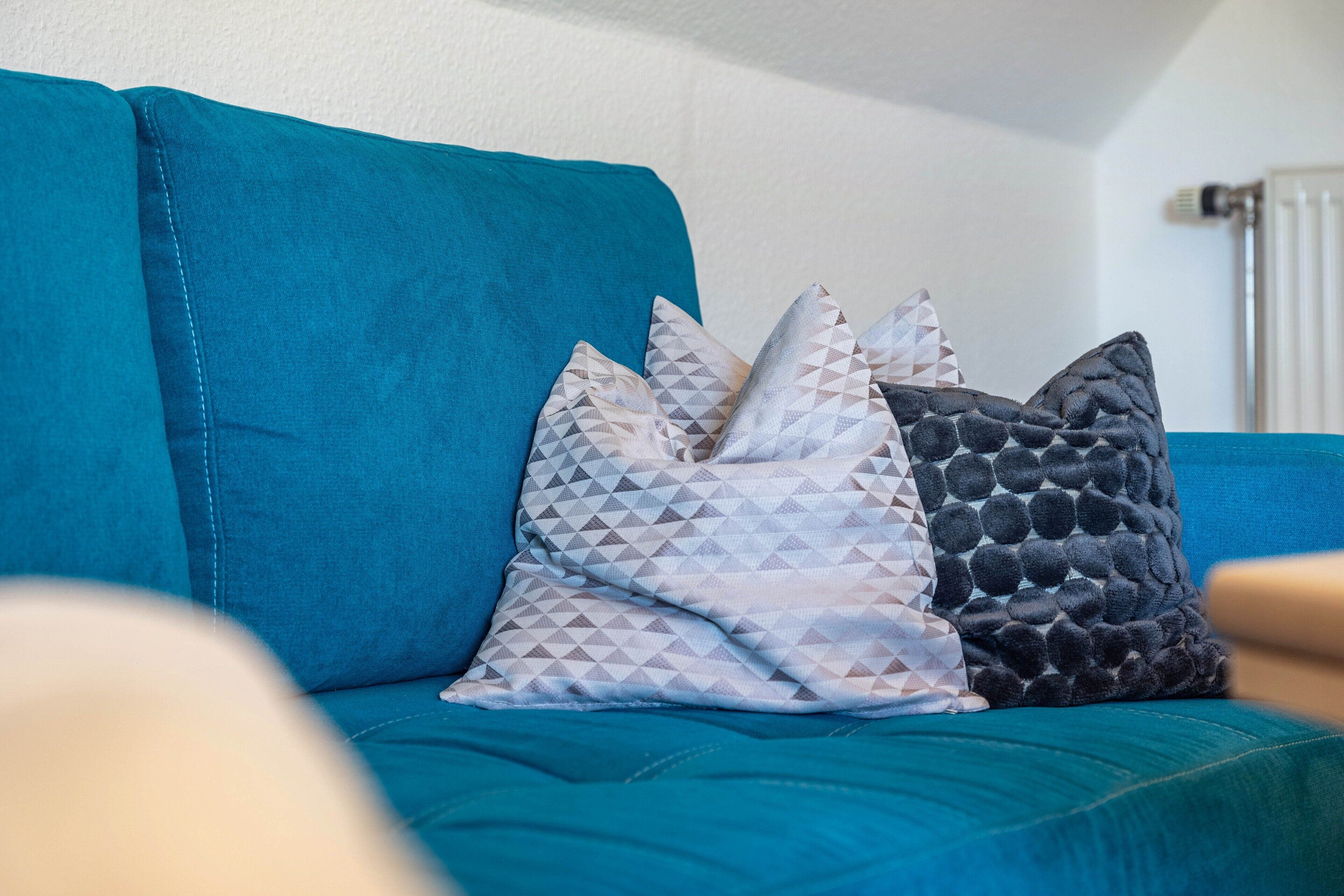 Un sofá turquesa con cojines estampados.
