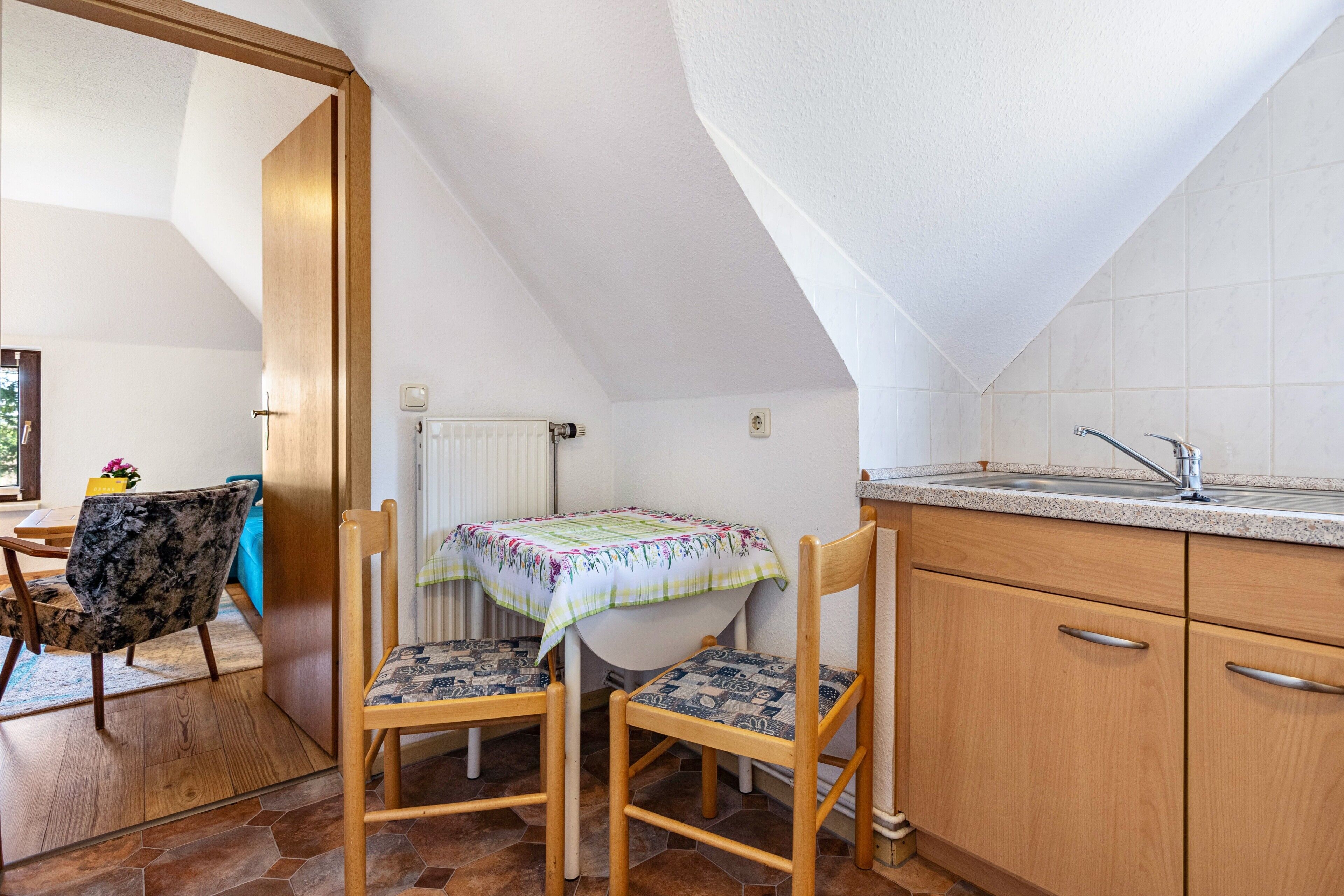 Une petite cuisine avec une table et des chaises, un radiateur et une fenêtre.