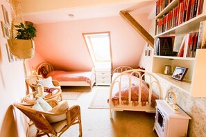 Um quarto aconchegante com cama, mesa de cabeceira, cadeira, estante e um pequeno aquecedor.