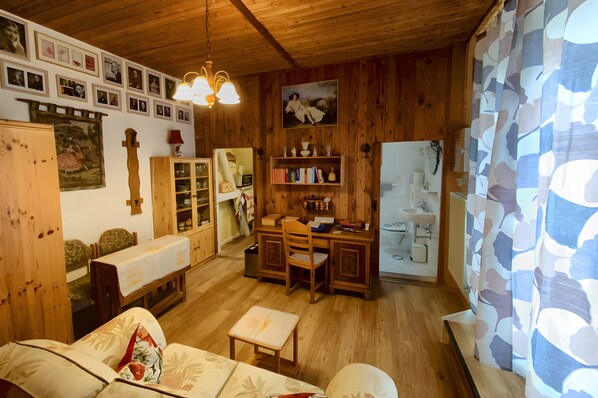 Una habitación acogedora con paredes de madera, una zona de comedor, una cocina y un baño.
