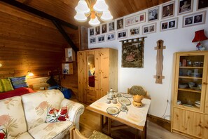 Una habitación acogedora con paredes de madera, una mesa de comedor con platos y tazas, un sofá con tapicería floral y una pared decorada con fotografías enmarcadas.