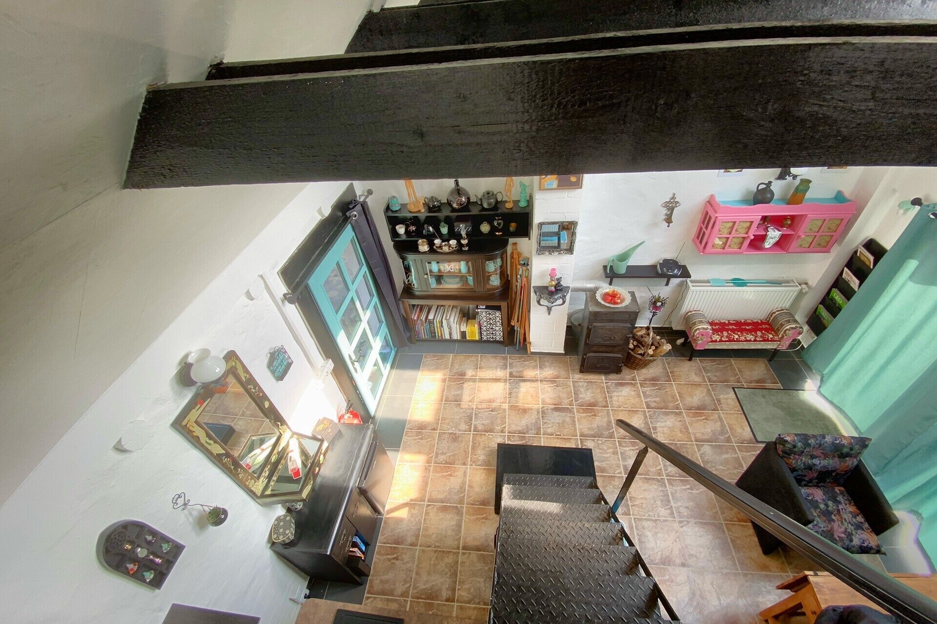 Ein Zimmer mit Treppe, einem kleinen Tisch mit Vase und Regalen mit diversen Gegenständen.