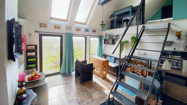 Een ruime kamer met een vide, een trap en uitzicht op de omgeving.
