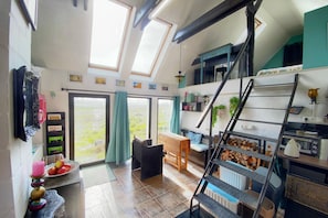 A spacious room with a loft area, a staircase, and a view of the outdoors.