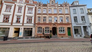 A historic building with a brick facade, multiple windows, and a green door.