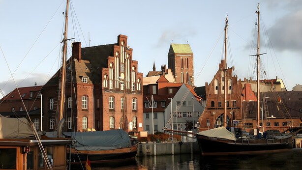 A harbor with historic buildings, a boat, and a small dock.
