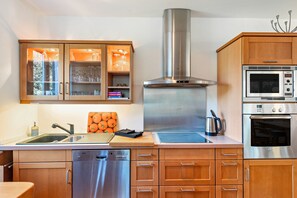 Une cuisine moderne dotée d’appareils électroménagers en acier inoxydable, de meubles en bois et d’un four encastré.