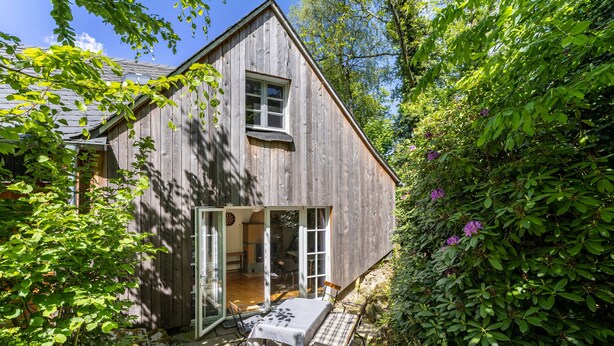 Ein Holzhaus mit Terrasse, Tisch und Stühlen.