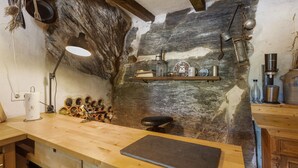 Eine rustikale Küche mit Holztischplatte, einer Hängelampe und einer Steinwand.