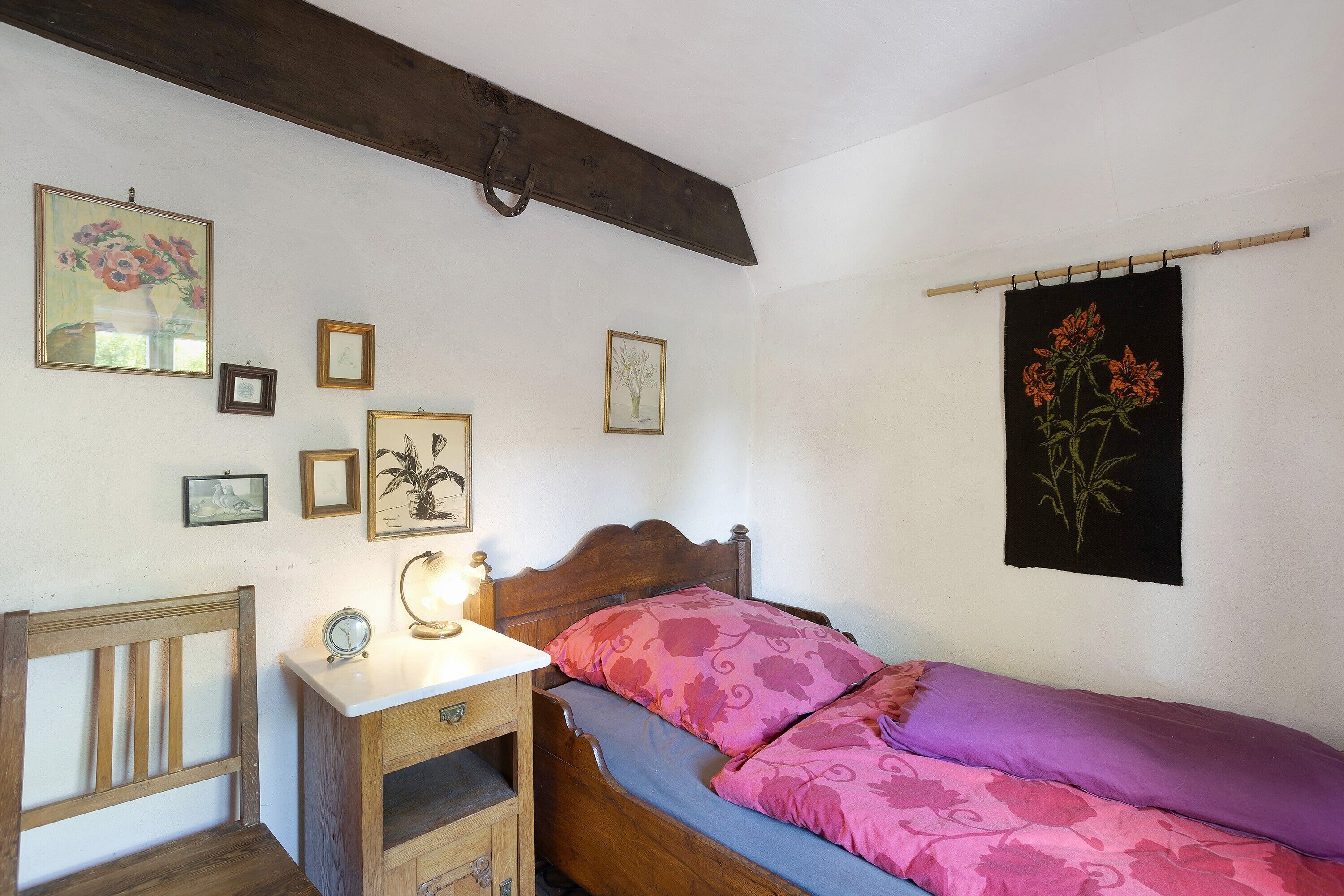 Une chambre à coucher avec un lit en bois, une table de chevet avec une lampe et des tableaux encadrés accrochés au mur.
