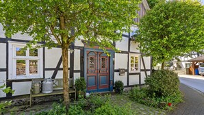 Ein traditionelles Gebäude mit einer markanten Tür, einem Fenster und einer kleinen Bank vor der Fassade.