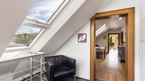 Een modern interieur met dakraam, een zwarte leren stoel, een eethoek en een keuken.